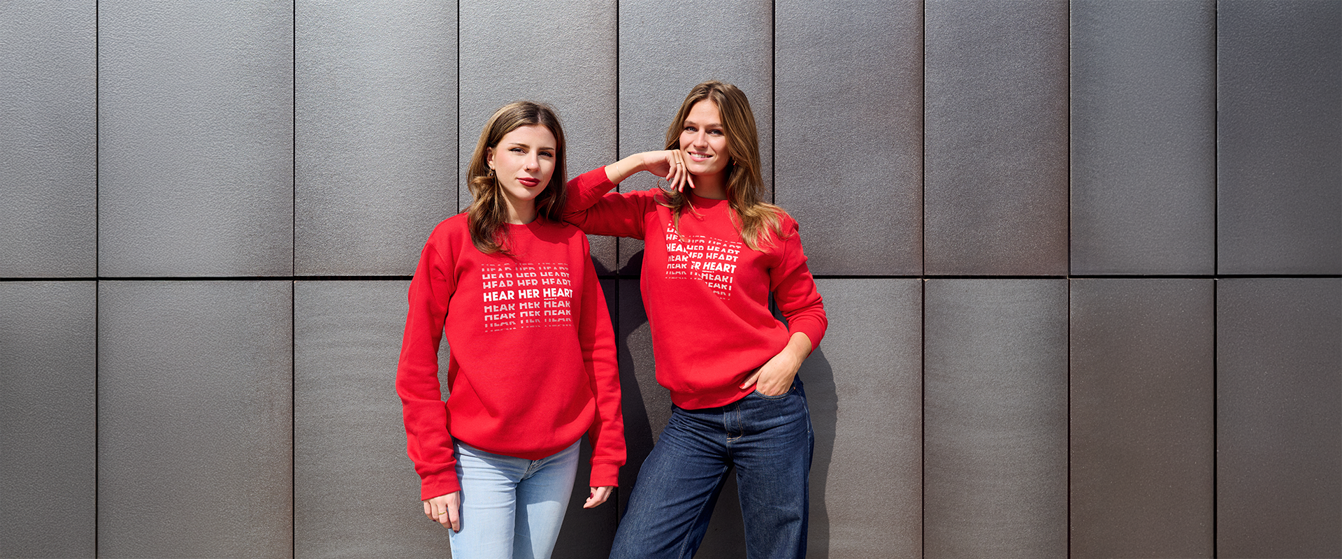 Twee vrouwen dragen trots de dress red day sweaters