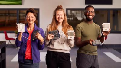 Drie personen poseren met een bloeddrukmeter