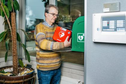 Man pakt AED uit kast