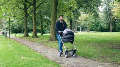Gui loopt met een kinderwagen door het park