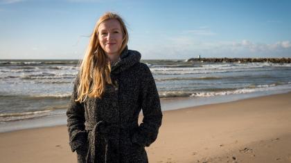 Elles staat lachend op het strand in het zonnetje