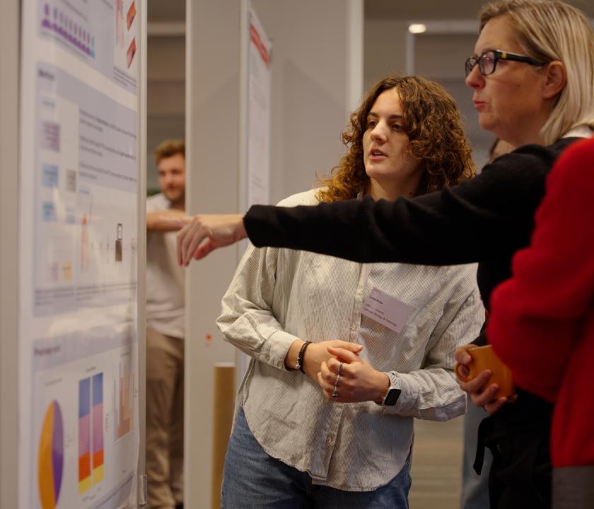 Drie mensen kijken naar een wetenschappelijke poster